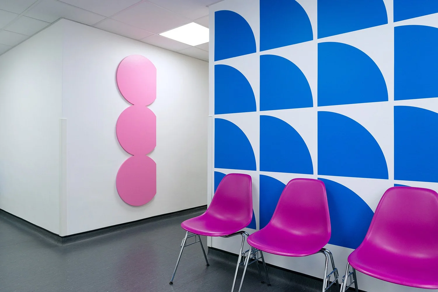 Blue geometric wall pattern beside pink chairs