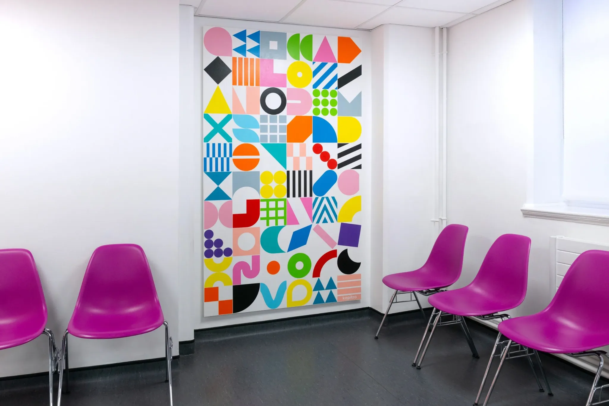 Colourful geometric poster surrounded by pink chairs