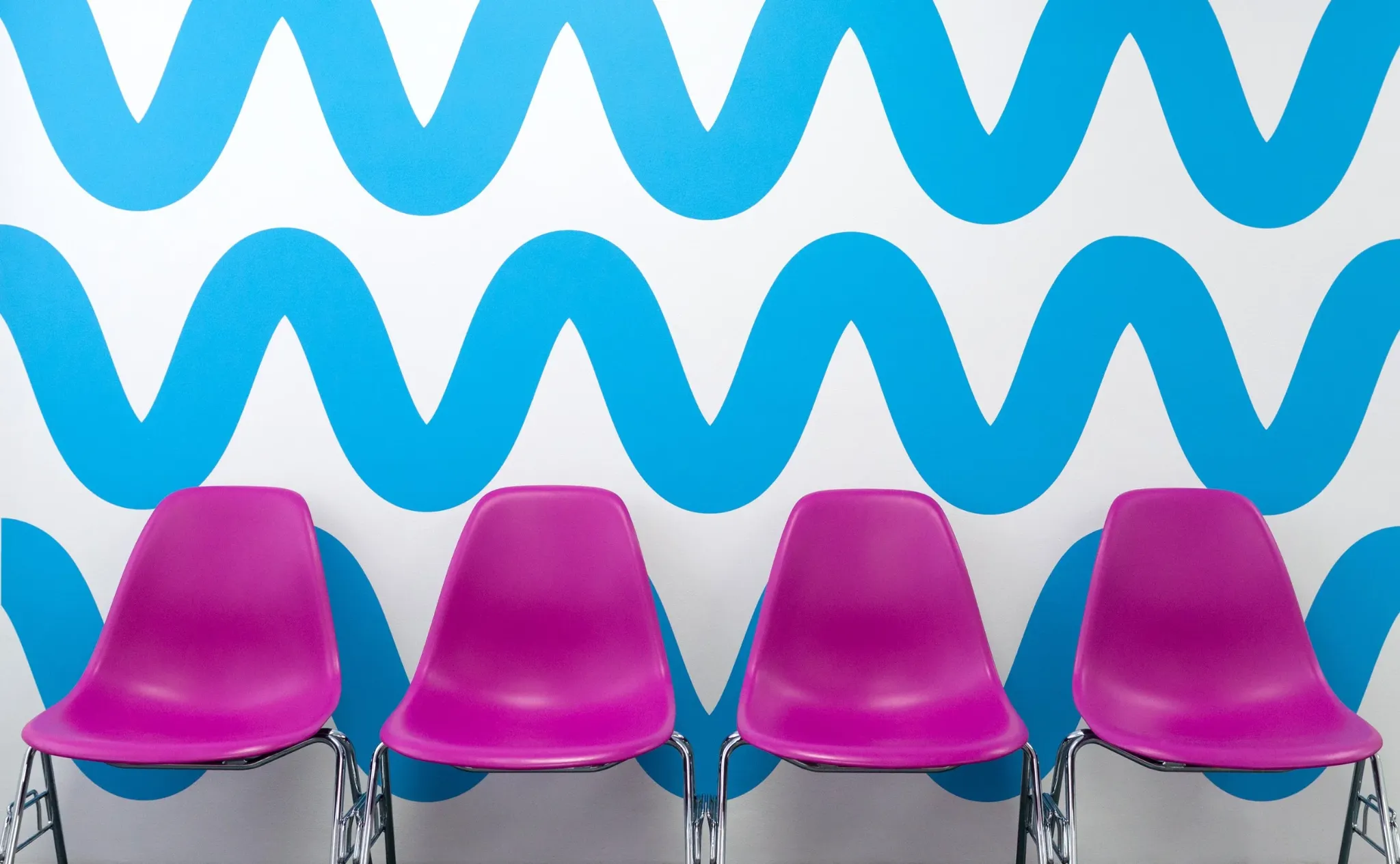 Blue wave pattern behind a row of pink chairs
